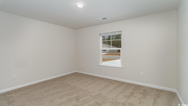 spare room with carpet flooring, baseboards, and visible vents