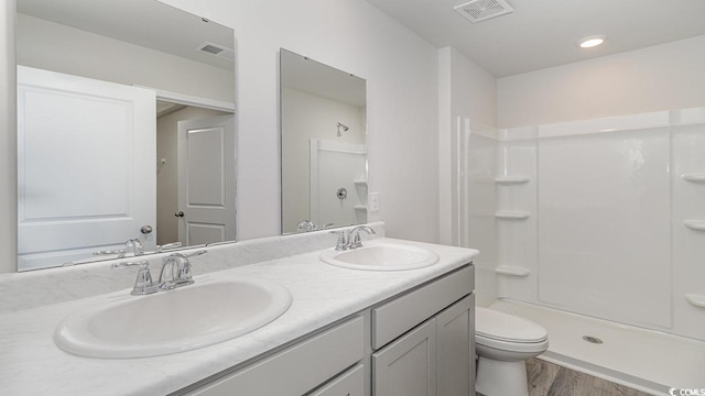 bathroom featuring a shower, hardwood / wood-style floors, vanity, and toilet