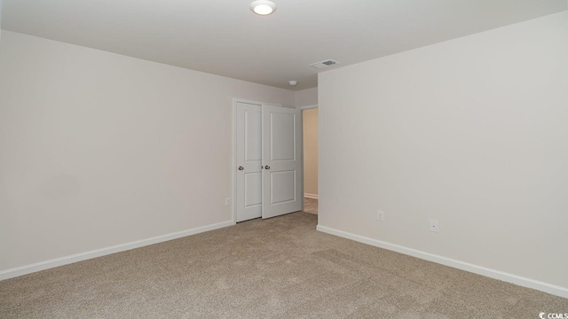 empty room with visible vents, light colored carpet, and baseboards