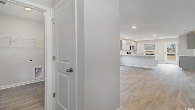 hall featuring recessed lighting, baseboards, and light wood-style flooring