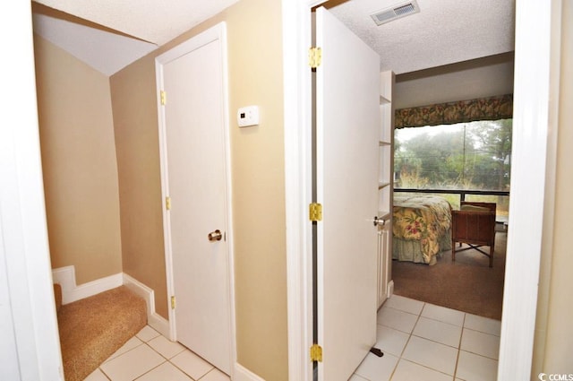 hall with a textured ceiling and light tile flooring