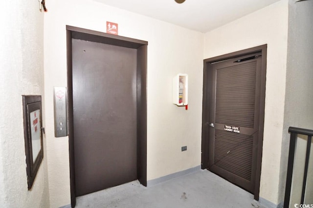 hall featuring concrete flooring and elevator