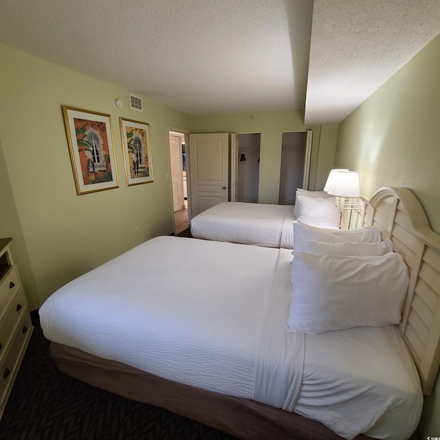 bedroom featuring dark carpet and a textured ceiling