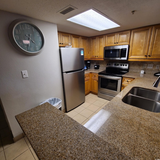 kitchen with backsplash, stainless steel appliances, light tile floors, and sink