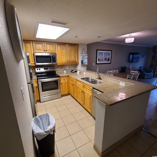 kitchen with stainless steel appliances, stone counters, light tile floors, sink, and kitchen peninsula