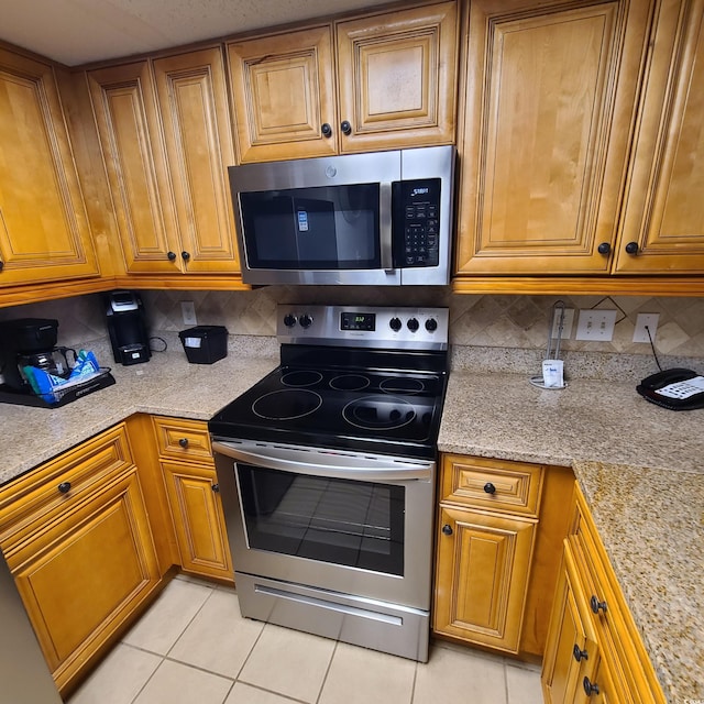 kitchen featuring appliances with stainless steel finishes, tasteful backsplash, and light stone countertops