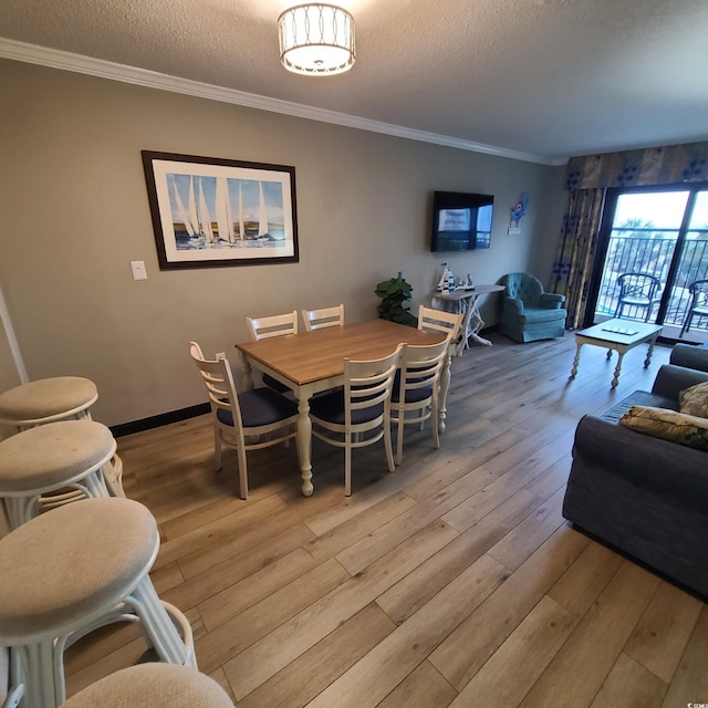 dining space with crown molding, light wood-type flooring, and a textured ceiling