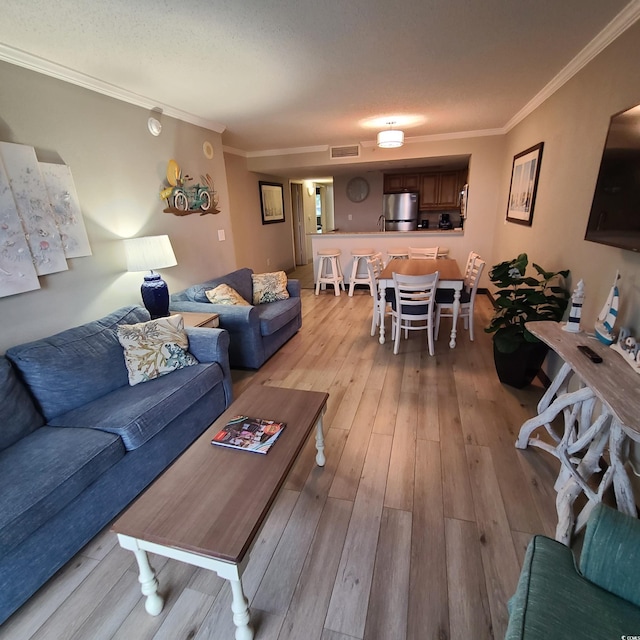 living room with ornamental molding and light hardwood / wood-style flooring