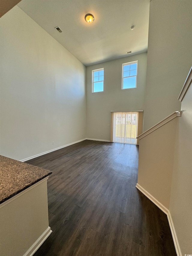 spare room featuring dark hardwood / wood-style flooring and a towering ceiling