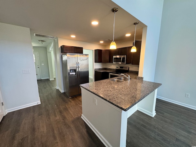 kitchen featuring hanging light fixtures, dark stone countertops, a breakfast bar, stainless steel appliances, and dark wood-type flooring