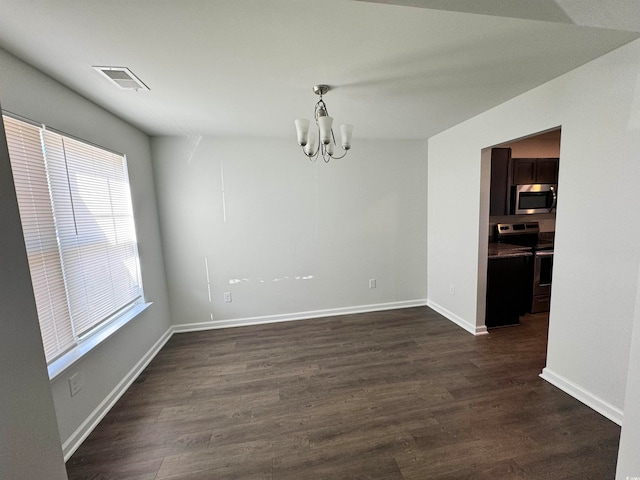 spare room featuring a chandelier and dark wood-type flooring