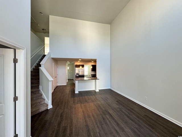 unfurnished living room with a high ceiling and dark hardwood / wood-style floors