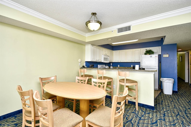 dining space with ornamental molding and a textured ceiling