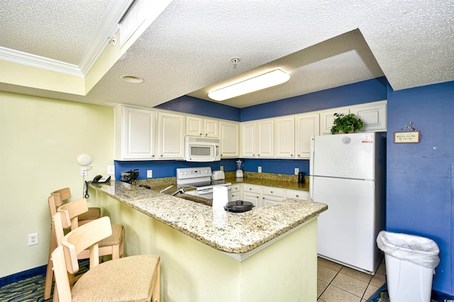 kitchen featuring a breakfast bar area, white appliances, light tile floors, kitchen peninsula, and ornamental molding