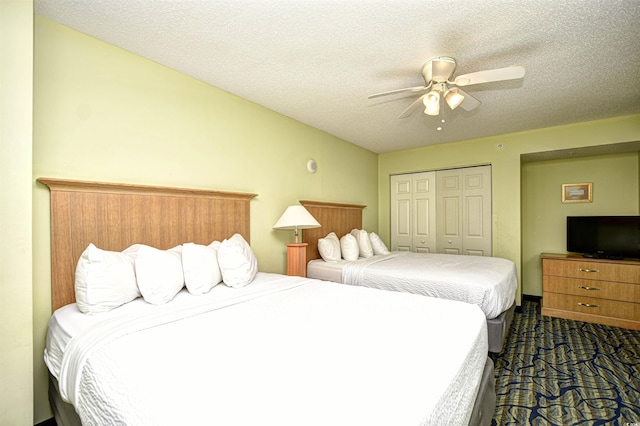 bedroom with a textured ceiling, a closet, ceiling fan, and dark colored carpet