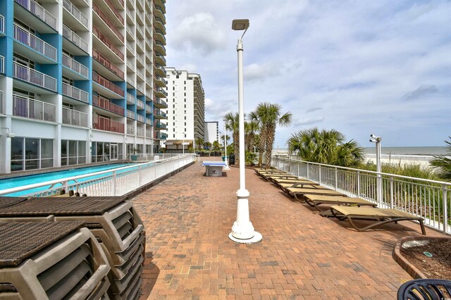 view of patio with a balcony, a community pool, and a water view