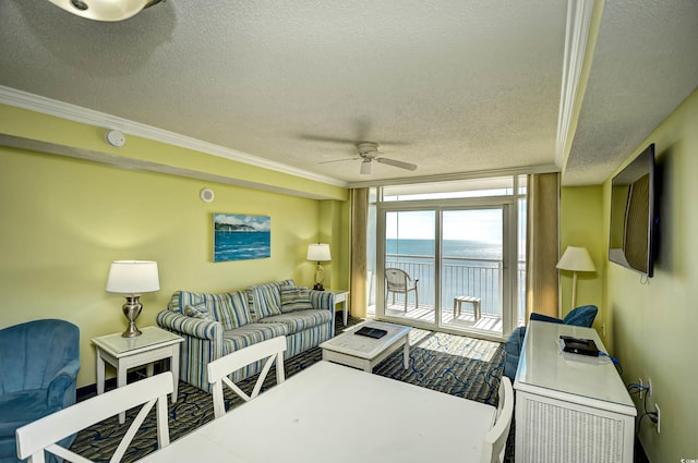 living room featuring a water view, ornamental molding, ceiling fan, and a textured ceiling