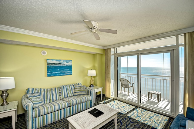 carpeted living room featuring ceiling fan, a water view, ornamental molding, and a textured ceiling