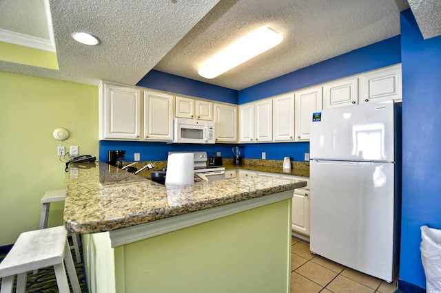 kitchen featuring light stone counters, a breakfast bar area, white appliances, light tile floors, and kitchen peninsula