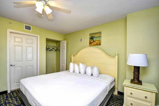 bedroom featuring ceiling fan, a textured ceiling, dark carpet, and a closet