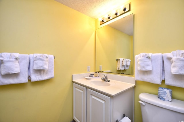 bathroom with a textured ceiling, toilet, and vanity