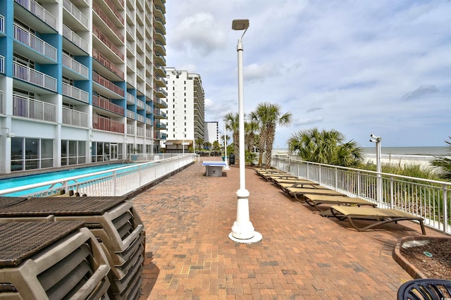 view of patio with a balcony, a community pool, and a water view