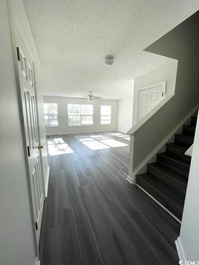 corridor with dark hardwood / wood-style flooring and a textured ceiling