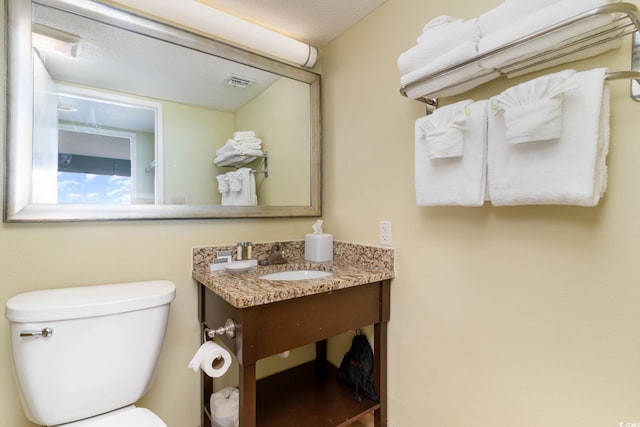 bathroom with toilet, a textured ceiling, and large vanity