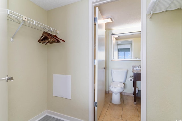 bathroom featuring toilet, tile flooring, and a textured ceiling