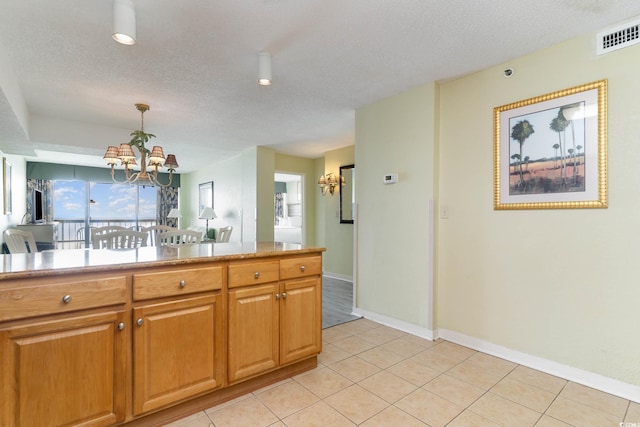 kitchen with a chandelier, pendant lighting, light tile floors, and a textured ceiling