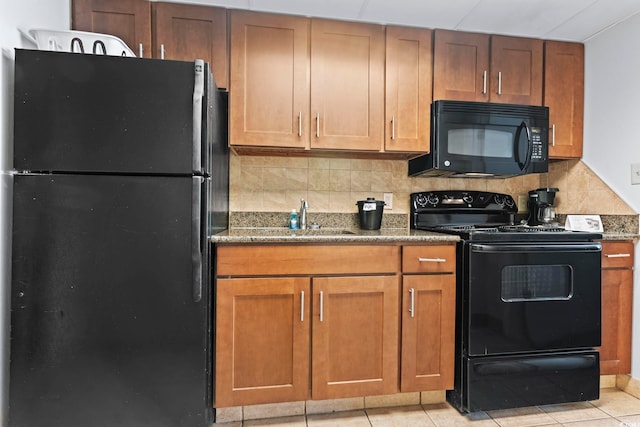 kitchen featuring dark stone counters, backsplash, black appliances, and light tile flooring