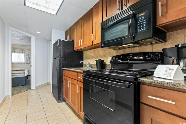 kitchen with light tile flooring, tasteful backsplash, dark stone countertops, and black appliances