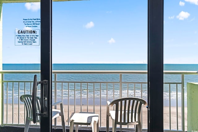 balcony with a water view and a view of the beach