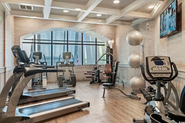 gym with coffered ceiling and light hardwood / wood-style floors