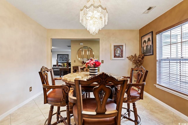 tiled dining room featuring an inviting chandelier and a textured ceiling