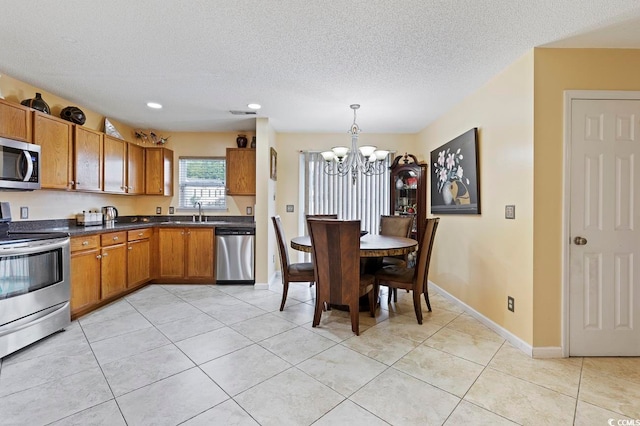 kitchen featuring appliances with stainless steel finishes, light tile floors, sink, decorative light fixtures, and an inviting chandelier