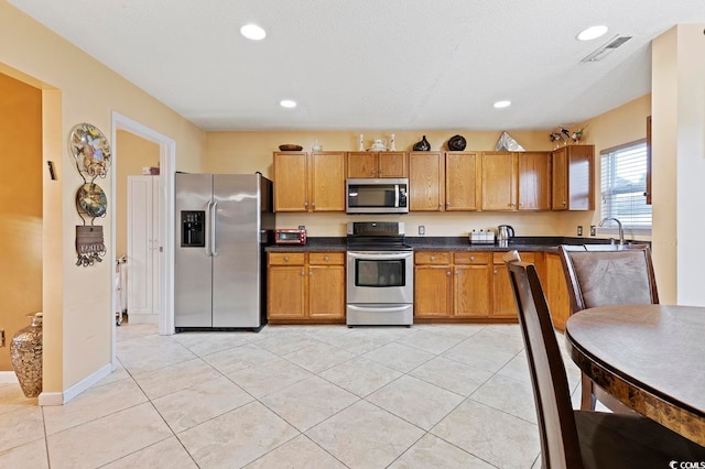 kitchen with sink, stainless steel appliances, and light tile floors