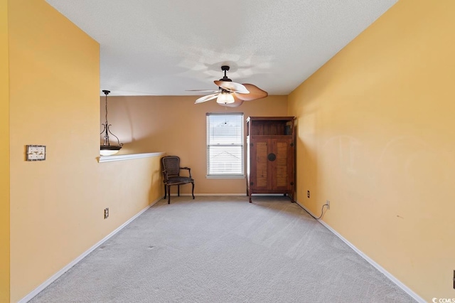 unfurnished room with light colored carpet, a textured ceiling, and ceiling fan