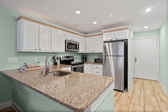 kitchen with appliances with stainless steel finishes, sink, kitchen peninsula, and white cabinets