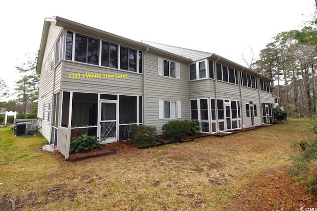 rear view of property with a yard, central AC unit, and a sunroom