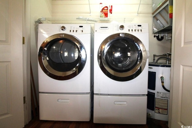 laundry area with dark wood-type flooring, washing machine and clothes dryer, and water heater