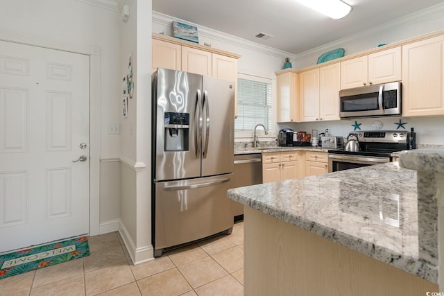 kitchen featuring appliances with stainless steel finishes, light tile flooring, light stone counters, sink, and crown molding