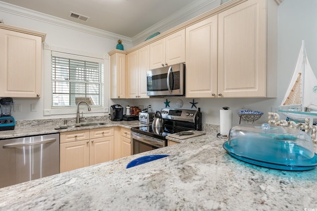 kitchen with appliances with stainless steel finishes, light stone counters, sink, and ornamental molding