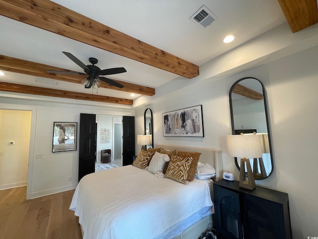 bedroom with ceiling fan, beamed ceiling, and wood-type flooring