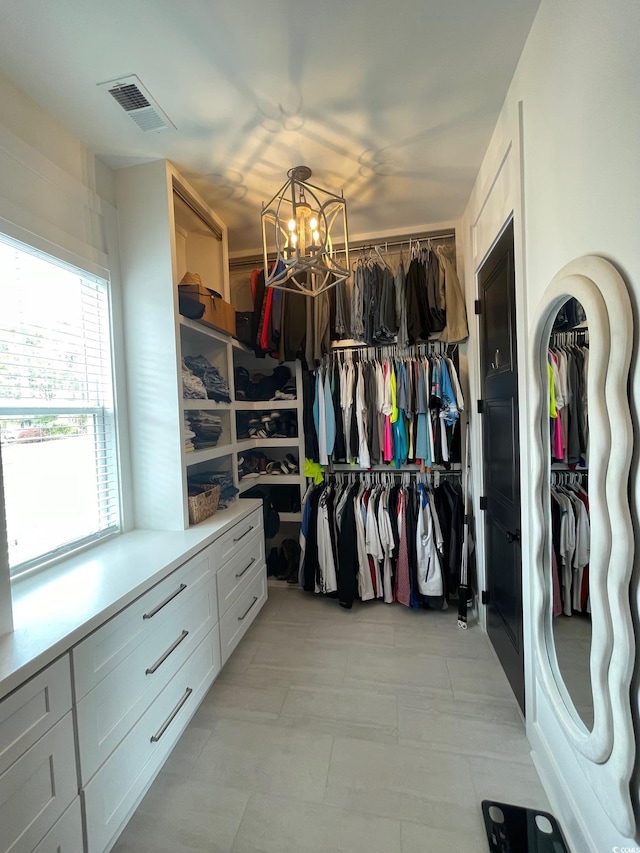 spacious closet with an inviting chandelier