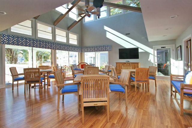 dining area featuring light hardwood / wood-style floors, ceiling fan, and a towering ceiling