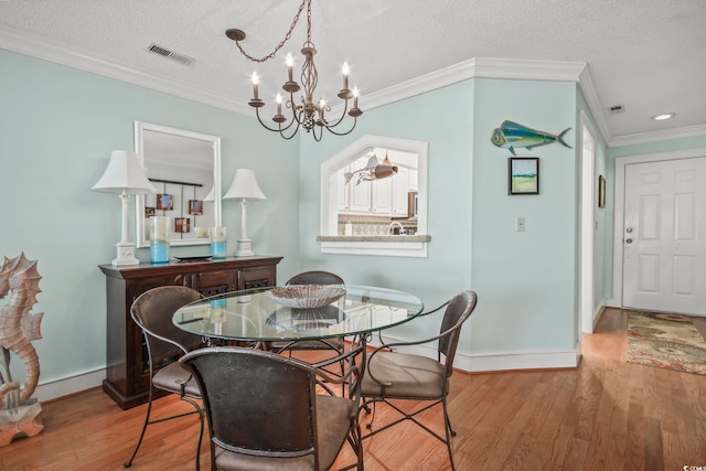 dining area featuring crown molding, light wood-type flooring, a chandelier, and a textured ceiling