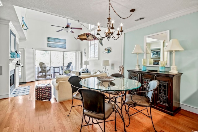 dining space with a textured ceiling, ceiling fan with notable chandelier, light hardwood / wood-style floors, and crown molding