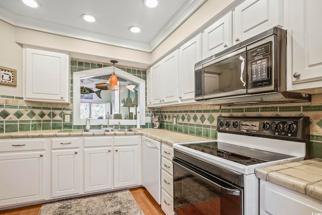 kitchen featuring tile countertops, tasteful backsplash, high quality stove, and white cabinetry