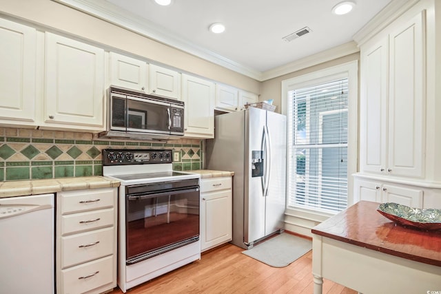 kitchen with white appliances, crown molding, white cabinets, tasteful backsplash, and light wood-type flooring